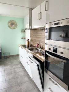 een keuken met witte kasten, een fornuis en een wastafel bij « L’Olympe » - à 300 M de la plage in Courseulles-sur-Mer