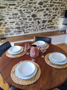 una mesa de madera con platos y copas de vino. en Le Nid - Fougères centre historique en Fougères