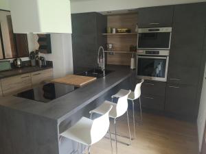 una cocina con encimera con taburetes blancos. en Appartement meublé tout confort, en Scionzier