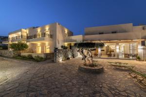 ein großes weißes Gebäude mit einem Baum davor in der Unterkunft Olive Grove Apartments in Elounda