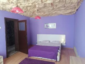 1 dormitorio con paredes de color púrpura y 1 cama con sábanas de color púrpura. en Кирил и Методий Апартамент en Burgas