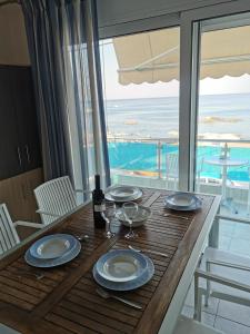 a table with plates and wine glasses and a view of the ocean at Tsampika's Sea View Home in Archangelos