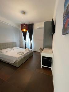 um quarto com uma cama, uma televisão e uma mesa em Relais Petruzzelli em Bari