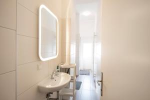 ein weißes Badezimmer mit einem Waschbecken und einem Spiegel in der Unterkunft City-Apartments Graz in Graz