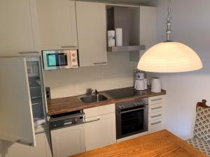 cocina con armarios blancos, fregadero y lámpara en Feriendorf am hohen Bogen Haus 98 EG, en Arrach