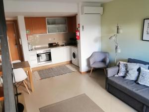 a living room with a couch and a kitchen at Apartamento Duplex - Cabanas Garden in Tavira