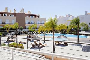 a resort with a pool and lounge chairs and trees at Apartamento Duplex - Cabanas Garden in Tavira
