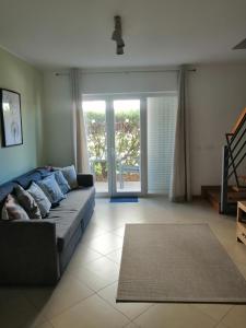 ein Wohnzimmer mit einem Sofa und einem großen Fenster in der Unterkunft Apartamento Duplex - Cabanas Garden in Tavira