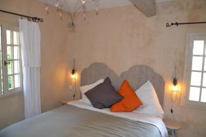 ein Schlafzimmer mit einem Bett mit orangefarbenen und grauen Kissen in der Unterkunft La Maison de Moustiers in Moustiers-Sainte-Marie