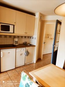 a kitchen with white cabinets and a microwave at Maisonnette mitoyenne 2 étoiles paisible piscine océan lac vélo marche idéal pour tous in Lacanau-Océan