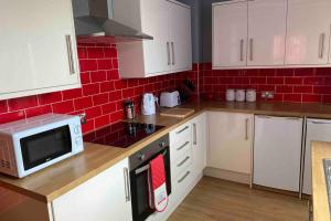 cocina con armarios blancos y microondas en Sited in lytham, not Moss side, Meadow Hse, entire Hse, sleeps 6 en Brown Moss Side