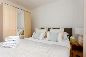 Schlafzimmer mit einem Bett mit weißer Bettwäsche und Kissen in der Unterkunft Flutes in Poole