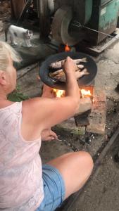 a woman is cooking food on a grill at Romantická chatka so saunou v prírode in Turany