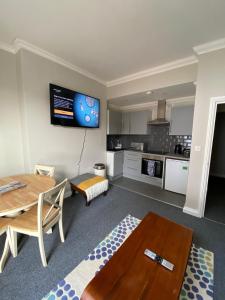 a living room with a table and a kitchen at Crofton House Garden Apartment in Ryde