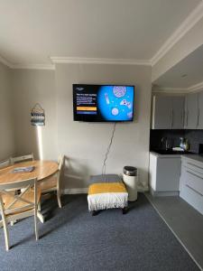 a kitchen with a table and a television on the wall at Crofton House Garden Apartment in Ryde