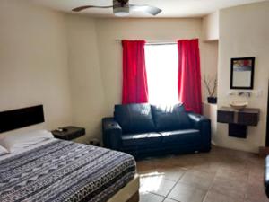 a bedroom with a bed and a couch and a window at Hotel Palacio By Rotamundos in Río Grande