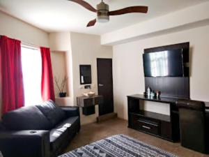 uma sala de estar com um sofá preto e uma televisão de ecrã plano em Hotel Palacio By Rotamundos em Río Grande