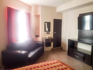 uma sala de estar com um sofá de couro preto e uma televisão em Hotel Palacio By Rotamundos em Río Grande