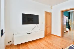 a white living room with a tv on a white wall at Logement L'échasseur à Jambes (NAMUR) in Namur