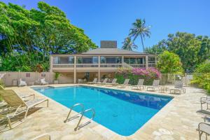 a swimming pool with chairs and a house at Pali Ke Kua #3 in Princeville