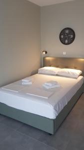 Bett in einem Zimmer mit einer Uhr an der Wand in der Unterkunft Iasonas View Studio in Néa Péramos