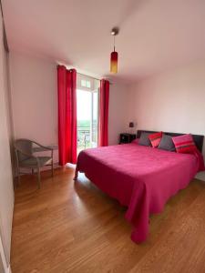 a bedroom with a large pink bed with red curtains at Hotel Residence Bellevue in Cambo-les-Bains