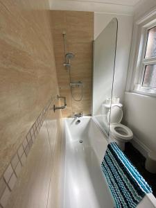 uma casa de banho com uma banheira, um WC e um chuveiro em Sandown Seaside Apartment Ground Floor 4 em Sandown
