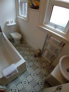 uma casa de banho com uma banheira, um WC e uma janela. em Sandown Seaside Apartment Ground Floor 4 em Sandown