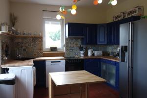 a kitchen with blue cabinets and a wooden table at Domaine du pavillon Gîte 15 personnes in Issy-lʼÉvêque