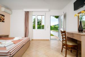 a hotel room with a bed and a desk and a door at Antigone Thassos Hotel in Limenas