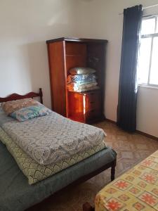 um quarto com uma cama, uma cômoda e uma janela em Apartamento perto de praia Dos Anjos em Arraial do Cabo