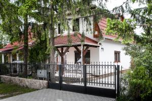 a black fence in front of a white house at Négy évszak apartmanház in Mezőkövesd