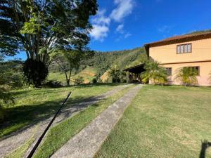 uma casa com um jardim relvado ao lado de um edifício em Casa de Campo com piscina e churrasqueira a 10min do Centro Domingos Martins em Domingos Martins