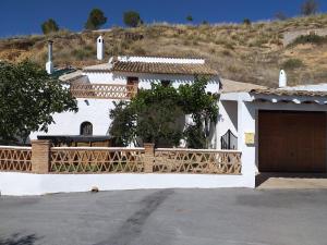 Casa blanca con valla de madera y garaje en Casa Cueva Pastor, en Fontanar