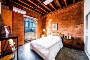 een slaapkamer met bakstenen muren, een bed en een raam bij Madero Homes in Buenos Aires