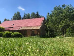a house with a red roof in a field at Pokoje nad Dymnem in Koczała +10 photos