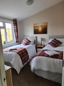 a hotel room with two beds and two windows at Captivatingly Stunning 2-Bed Cabin in Bridlington in Bridlington