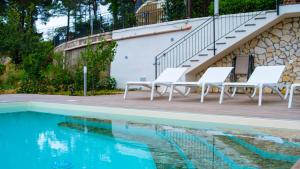 een zwembad met witte stoelen naast een trap bij La Villetta di Cefalù in Cefalù