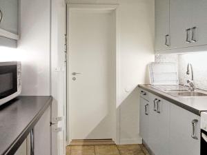 een witte keuken met een wastafel en een magnetron bij 5 person holiday home in TRELLEBORG in Trelleborg