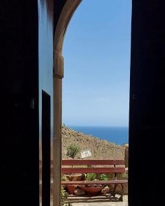 uma vista para um banco e para o oceano a partir de uma janela em La Casa sul Blu Albergo Diffuso em Pisciotta