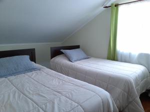 dwa łóżka w pokoju z oknem w obiekcie Casa Ana María w mieście Coquimbo