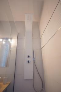 a shower in a white bathroom with a hose at HOME GANUSHA COSY 3 CHAMBRES PARKING GRATUIT BALCON in Grenoble