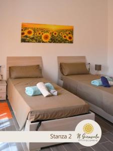 2 camas en una habitación con un cuadro en la pared en IL GIRASOLE, en Porto Torres