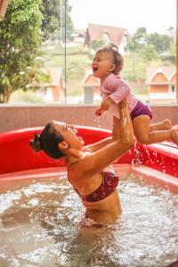 una donna che tiene un bambino in una piscina d'acqua di Hotel Fazenda China Park a Pedra Azul