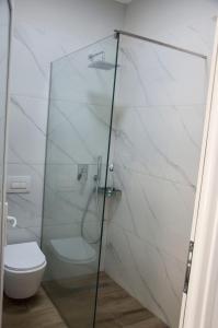 ein Bad mit einer Glasdusche und einem WC in der Unterkunft Heaven Beach Sarandë in Sarandë