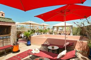 une terrasse avec un parasol rouge, une table et des chaises dans l'établissement Arabian Riad Marrakech, à Marrakech