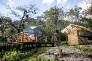 uma tenda e uma casa com um deque de madeira em Yátaro Refugio Glamping em La Vega