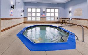 a jacuzzi tub in a waiting room with tables and chairs at Holiday Inn Express Wixom, an IHG Hotel in Wixom