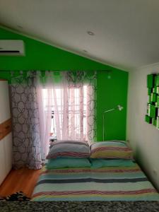 a green bedroom with a bed and a window at Apartment Lavanda in Mali Lošinj