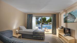 a hotel room with a bed and a couch and a television at Ephesia Holiday Beach Club in Kuşadası